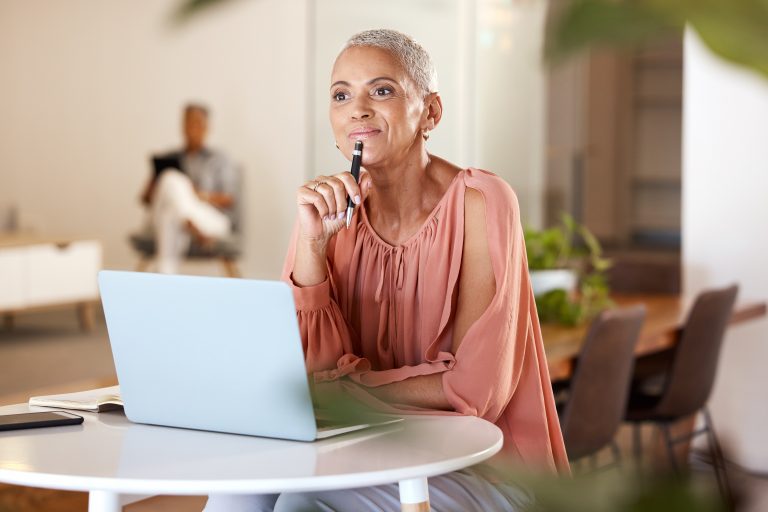 mature woman with idea for creative startup business or schedule planning in notebook at desk. Freelance worker, designer or writer, pen in hand working on ideas in modern office.