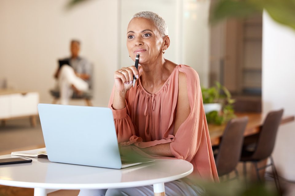 mature woman with idea for creative startup business or schedule planning in notebook at desk. Freelance worker, designer or writer, pen in hand working on ideas in modern office.