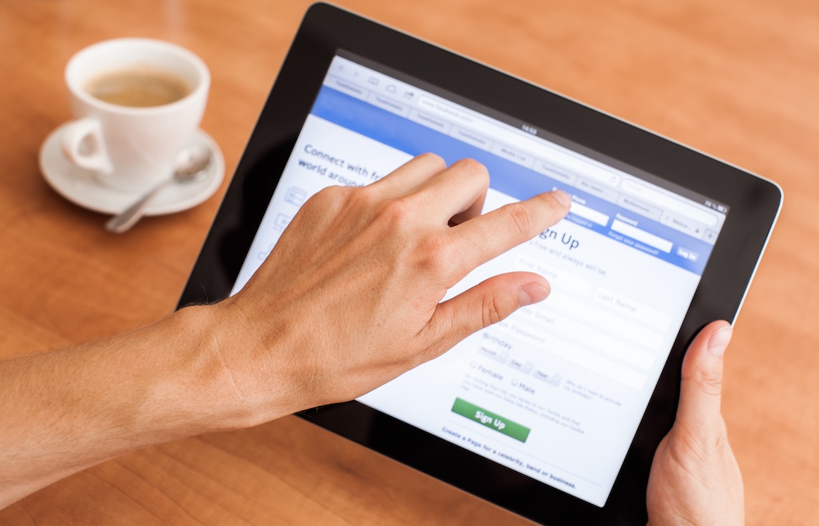 Hands holding tablet computer signing up for a Facebook account