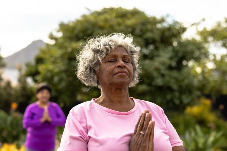 African american senior woman with eyes closed meditating against trees