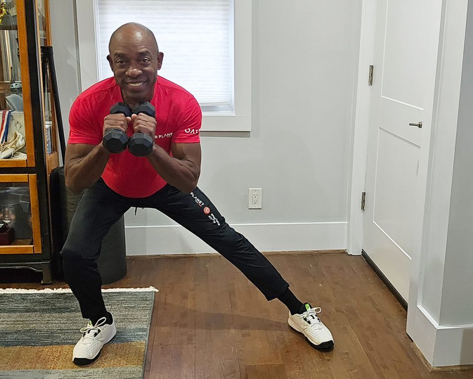 senior african american man exercising with weights squatting to side