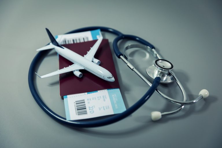 passport with flight ticket and stethoscope on gray background