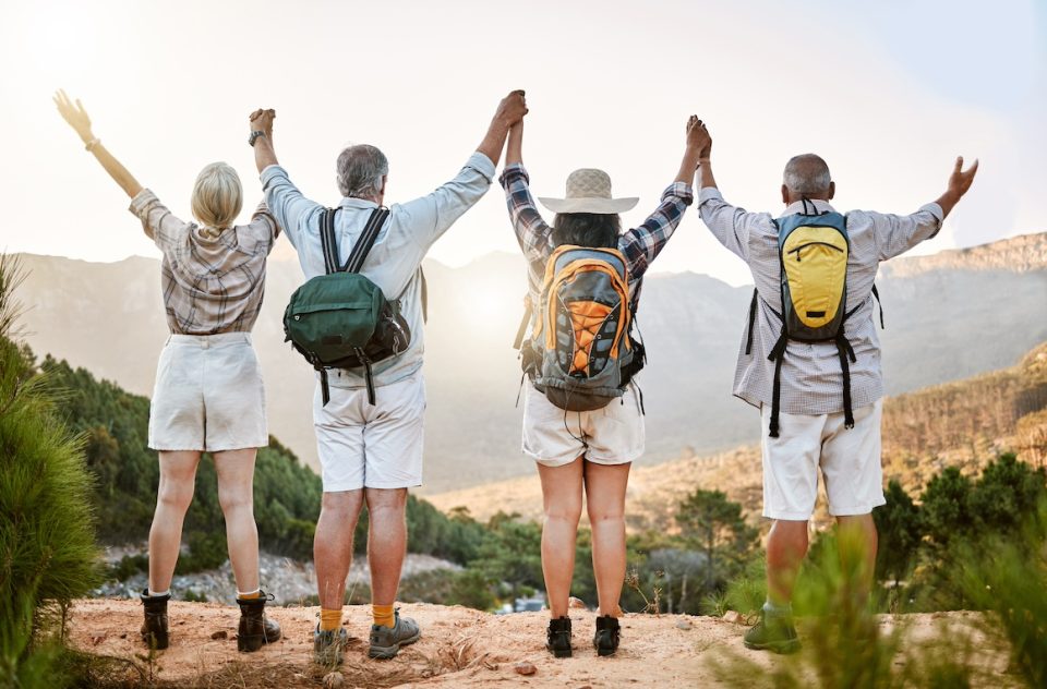 a group of senior friends taking a mountain hike and enjoying the view.