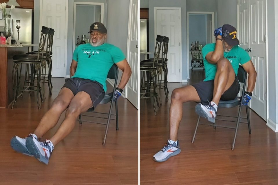 Senior African American man in green shirt and black shorts doing core exercises while seated in chair